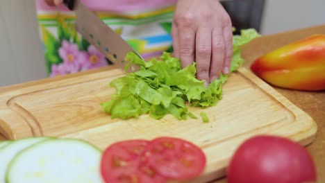 Female-hands-of-housewife-with-a-knife-cut-fresh-lettuce-on-a-chopping-Board-kitchen-table